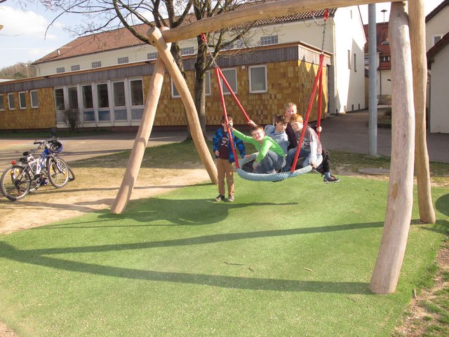 Spielplatz an der Grundschule mit Kindern auf Schaukel